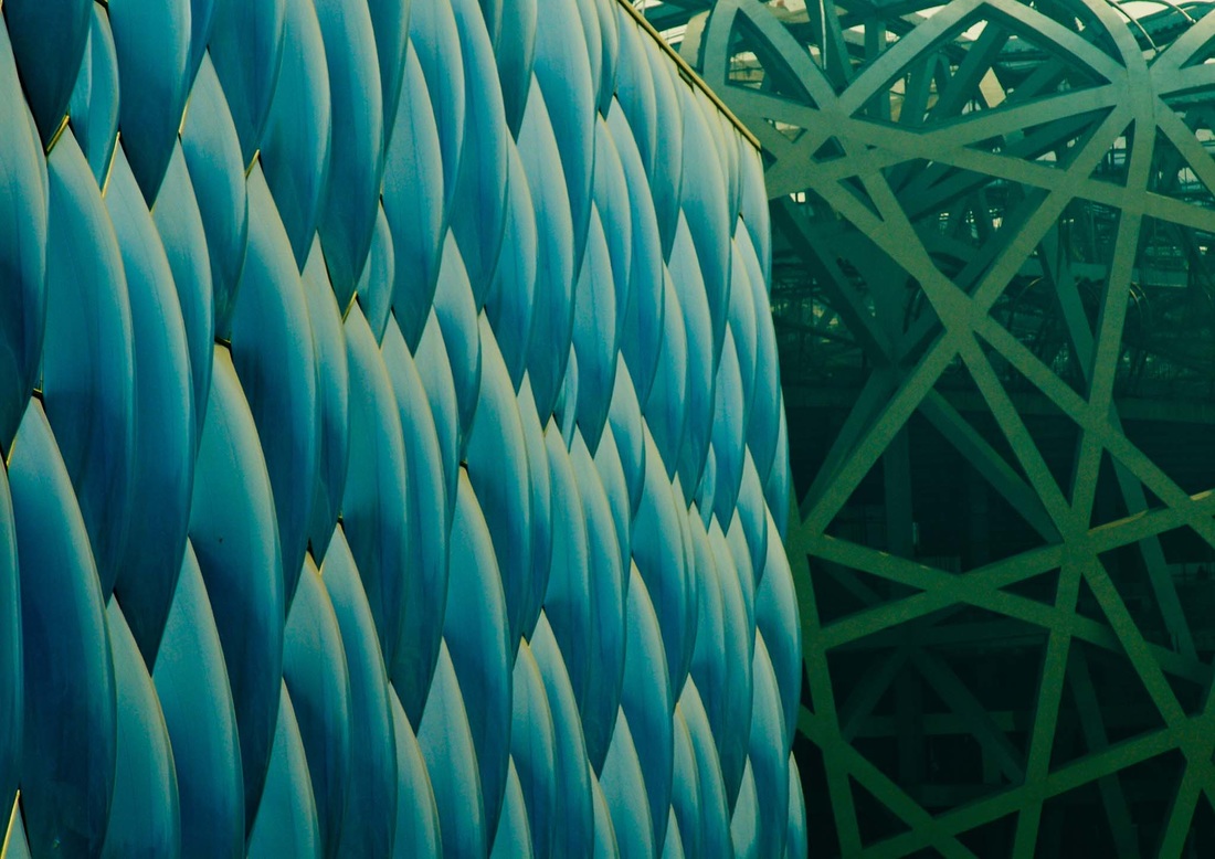 Blue bubble facade of the Beijing National Aquatics Centre beside the steel lattice of the National Stadium